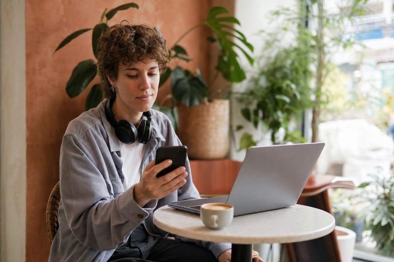 Editorial photo: a musician typing a message on a laptop with headphones and a notebook nearby, focused desk lighting, no readable text